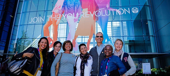 Provo Experience Nu Skin distributors pose for a picture with Nu Skin executive (put name of person if you can confirm who that is) in front of the Nu Skin corporate office in Provo, Utah.